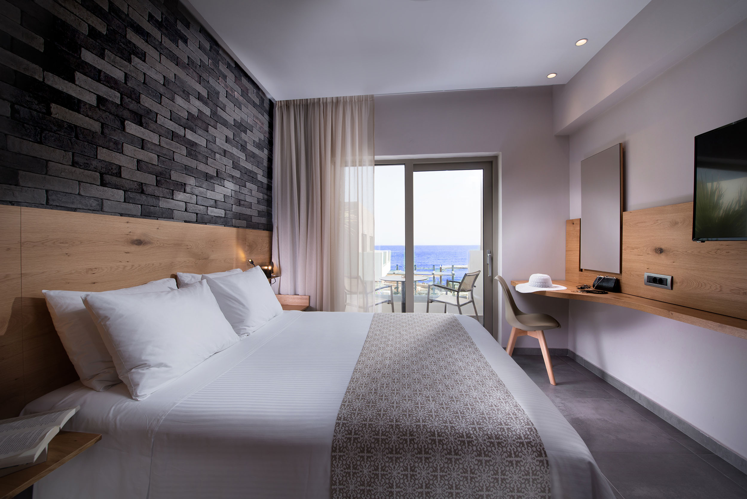 Cactus bay hotel room with a double bed, a TV and a balcony overlooking the sea