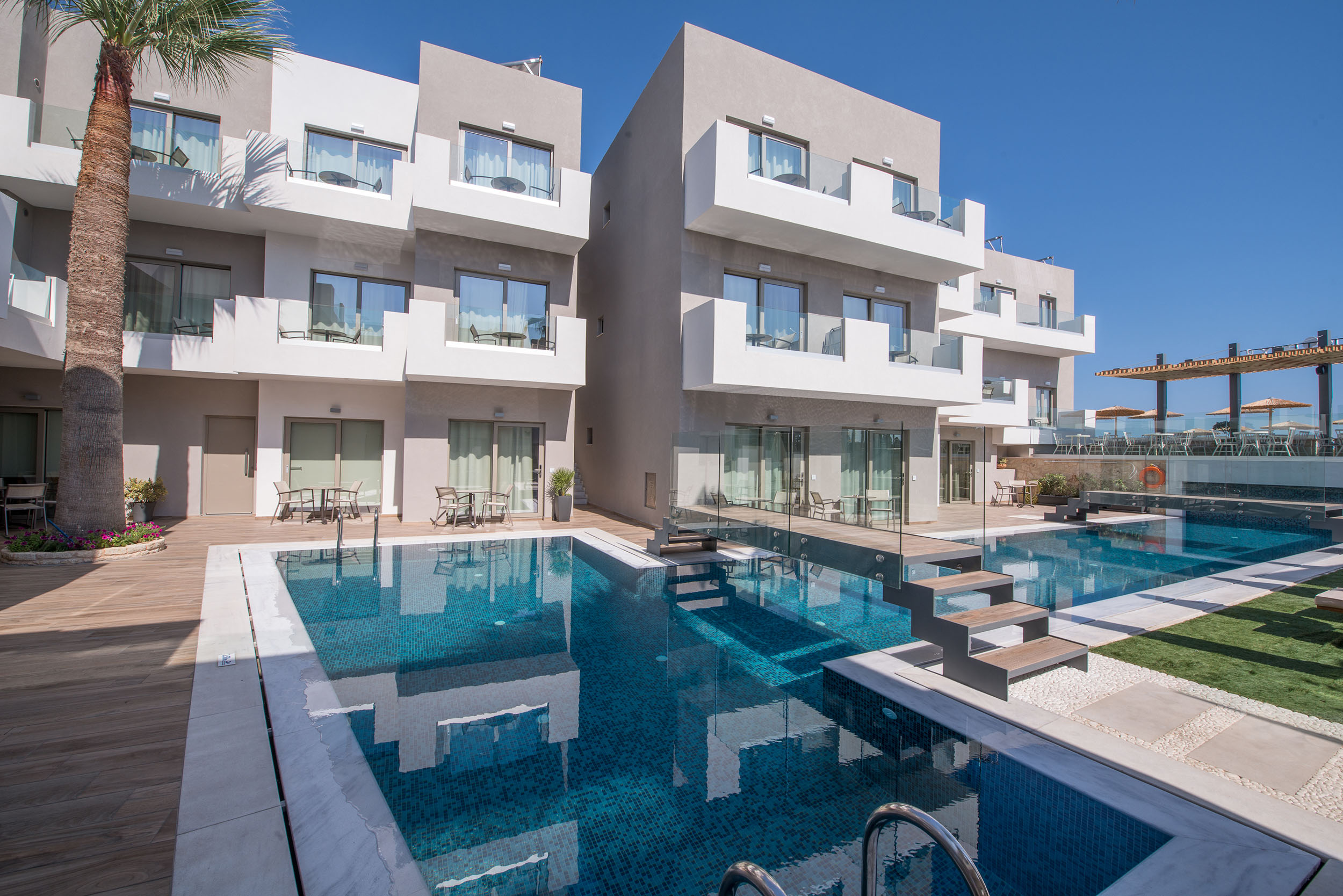 Exterior view of Cactus Bay Hotel Rooms overlooking the pool and palm trees