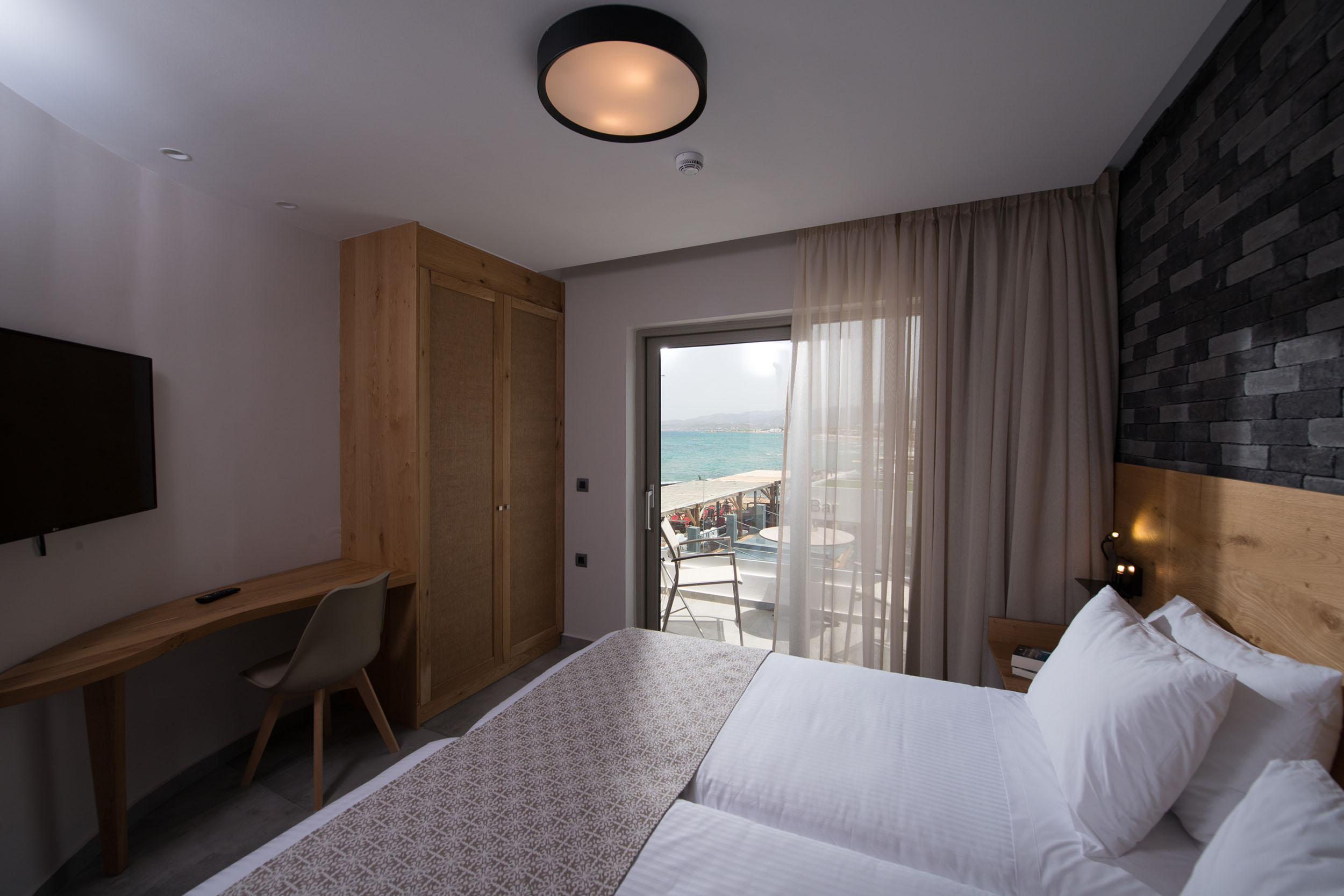 Cactus bay hotel suite with a double bed, a TV and a balcony overlooking the sea