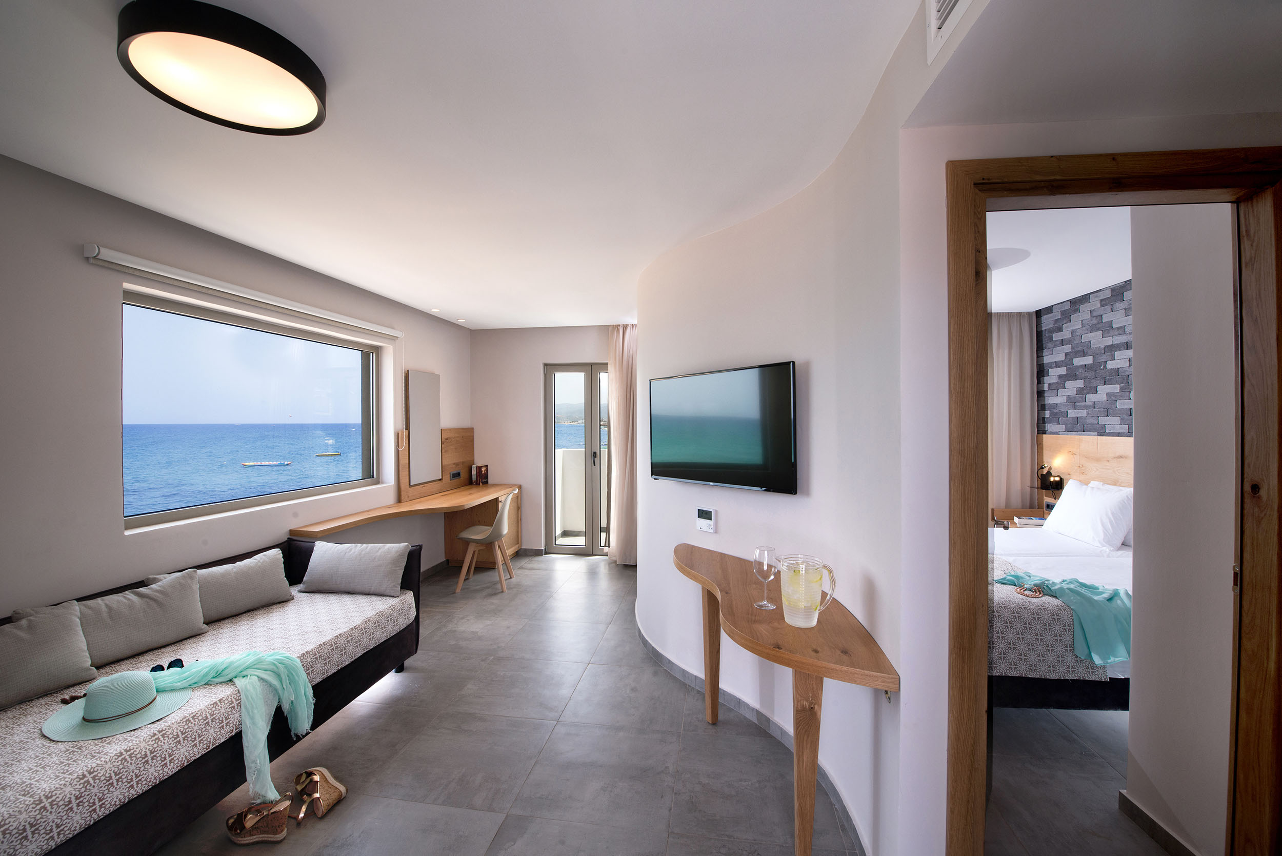 Σουίτα ξενοδοχείου Cactus bay με ένα διπλό κρεβάτι μία τηλεόραση και μπαλκόνι με θέα την θάλασσα